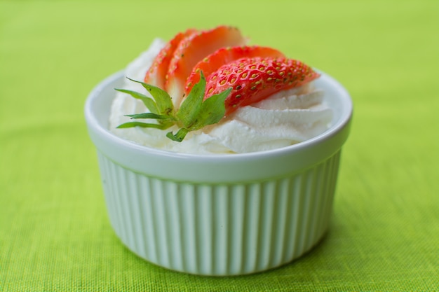 Creme de queijo em uma tigela de cerâmica branca com morangos em verde