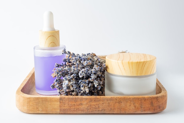 Creme de soro de óleos de lavanda e flores de lavanda em bandeja de madeira Produtos cosméticos para cuidados com a pele Conjunto de produtos de beleza naturais de spa Óleo essencial de lavanda soro de óleo de massagem corporal manteiga líquido