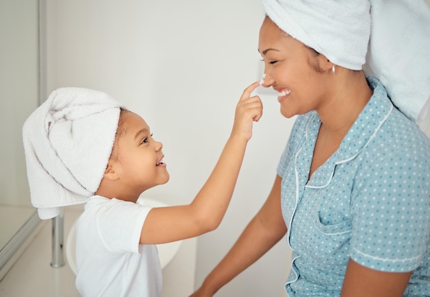 Creme facial de mãe e menina no banheiro aplicam cosméticos de beleza e produto de loção para rotina matinal de chuveiro Sorriso de felicidade ou mãe feliz e criança adoram creme de cuidados com a pele em casa