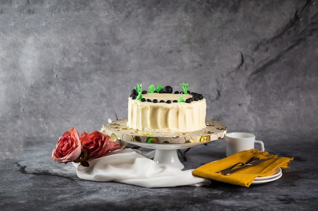 Creme fresco de bolo branco de mirtilo com faca e garfo de flores rosa servido a bordo isolado na vista lateral do guardanapo de comida assada no café