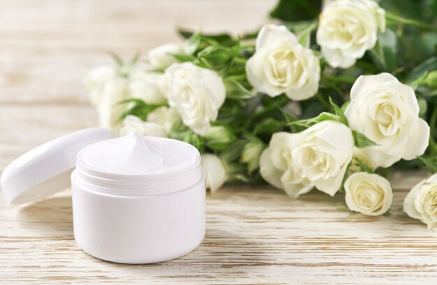 Creme hidratante para peles sensíveis, cosmético de spa e produto de limpeza natural para a pele em um fundo de rosas brancas.