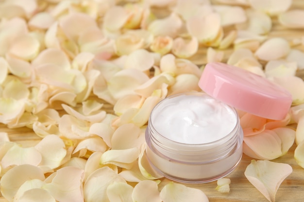 Creme in Rosenblättern. Kosmetik für Gesicht und Körper in rosa Flaschen mit frischen Rosen. Spa. Platz für Text.