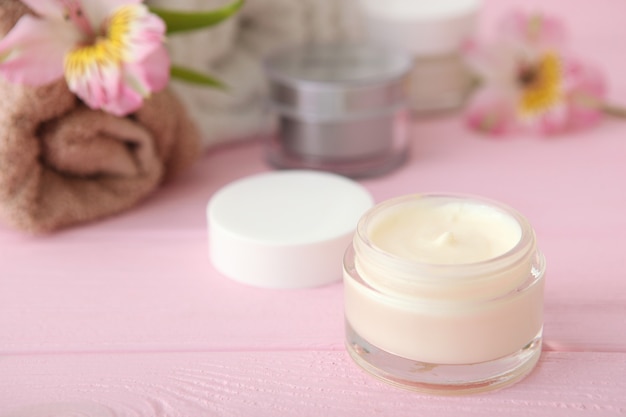 Creme para a pele e flores na mesa, cosméticos para cuidar da pele