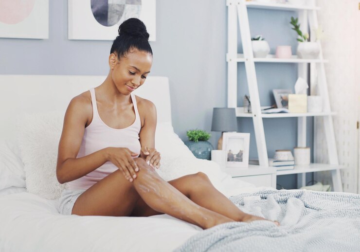 Foto creme pernas e mulher na cama com cuidado da pele rotina matinal e resultados saudáveis com o produto relaxe sorriso e menina no quarto com hidratante cosmético para dermatologia pele lisa e depilação