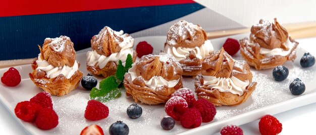 Creme puff mit Beeren und Zuckerpulver auf weißem Hintergrund Hausgemachte Creme puffs Kuchen köstliche französische Choux puffs Desserts auf dem Teller