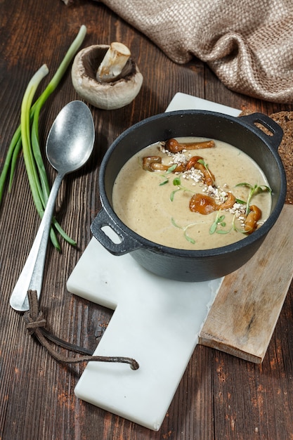 Cremesuppe mit Pilzen und frischem Pfifferlingpilz auf hölzernem rustikalem Hintergrund