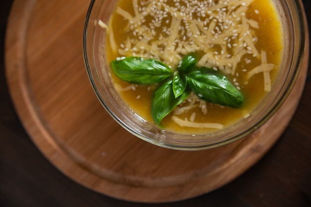 Cremesuppe von Zucchini mit Käse-Sesam und dekoriert mit Basilikumblatt auf einem Holzbrett