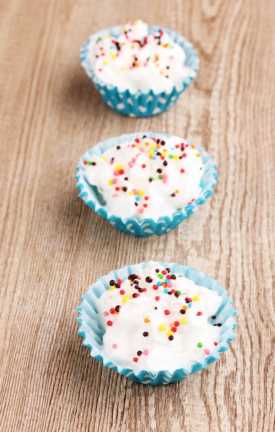 Cremige kleine Kuchen auf hölzernem Hintergrund