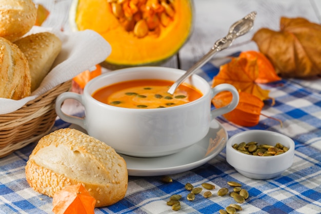 Cremige Kürbissuppe mit Kürbiskernen und Sahne in einer weißen Schüssel schließen oben