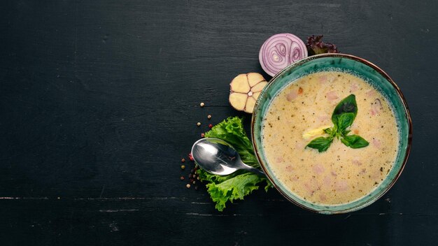 Cremige Suppe mit Speck Hühnerei Gemüse und Basilikum Auf einem Holztisch Draufsicht Kopieren Sie Platz