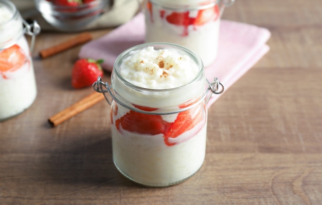 Cremiger Milchreis mit Erdbeere im Glas auf Holztisch