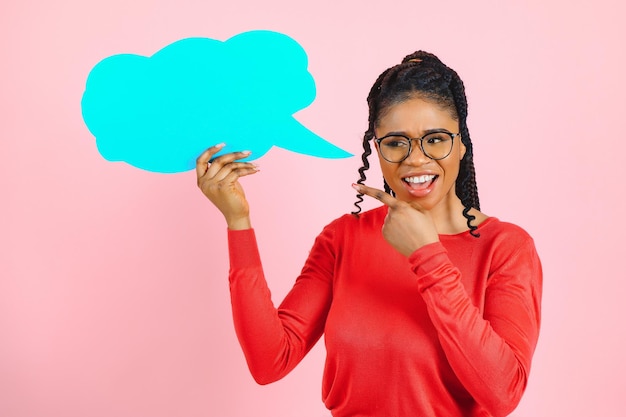 Creo que una mujer afro pensativa mirando un bocadillo de diálogo en blanco tocando su barbilla copyspace rosa en la pared del estudio