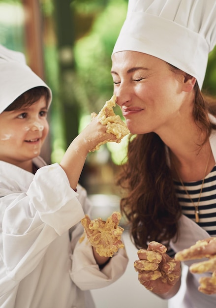 Creo que tienes algo aquí. Fotografía de una madre y su hijo pequeño con masa en las manos horneando juntos en la cocina.