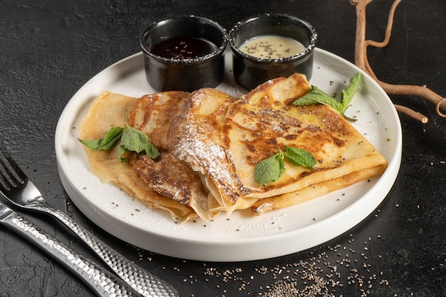 Crêpe mit Beerensauce, Minze und Chiasamen. Pfannkuchen aus Eiern und Mehl. Ein traditionelles Gericht von Maslenitsa