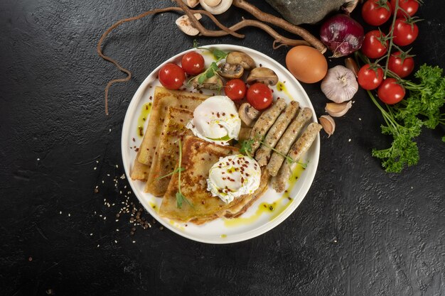 Crêpe mit gegrillten Hähnchenwürsten, Pilzen, Kirschtomaten und pochiertem Ei. Ein warmes kontinentales Frühstück