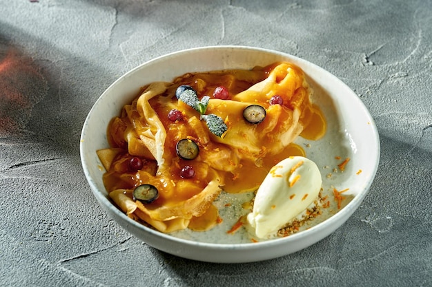 Crepe suzette clásica con helado de mermelada de naranja y bayas en un plato Un delicioso postre