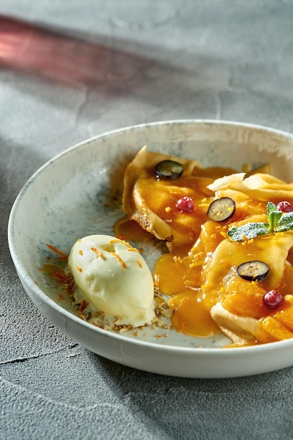 Crepe suzette clásica con helado de mermelada de naranja y bayas en un plato Un delicioso postre