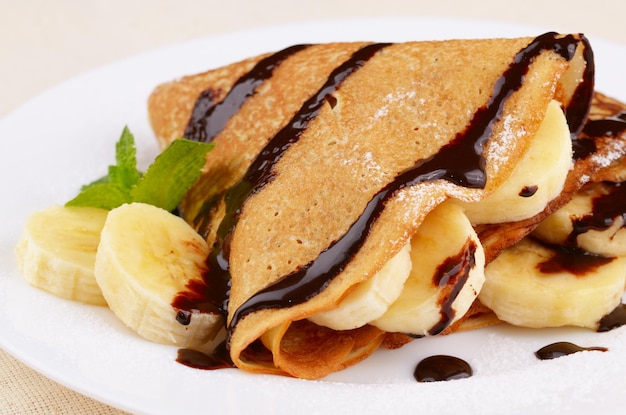 Crepes à francesa com banana, calda de chocolate e açúcar em pó