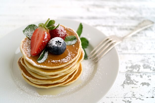 Crepes americanas con las bayas en un fondo ligero.