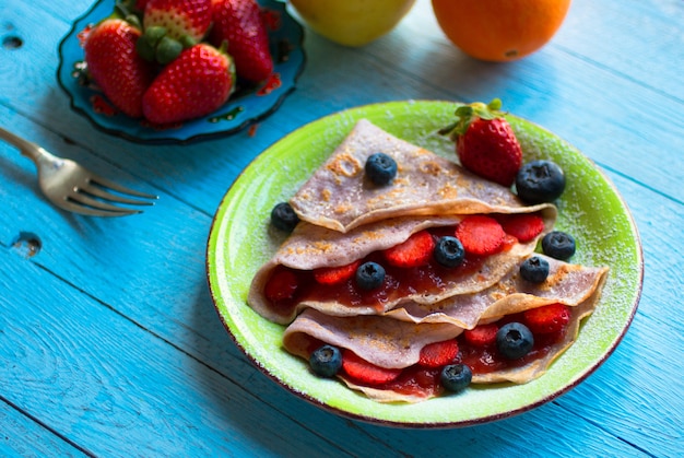 Crepes caseros frescos servidos en un plato con fresas y arándanos