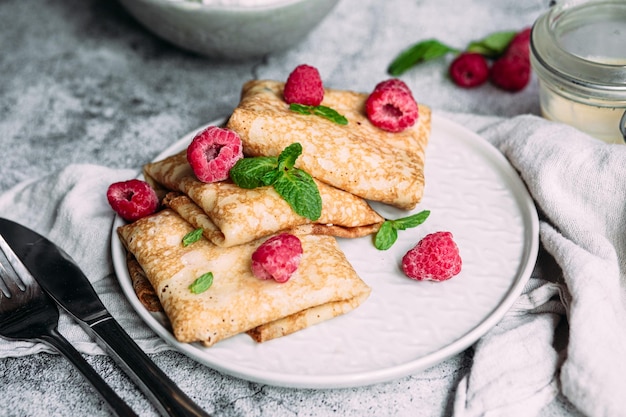 Crepes com requeijão caseiro, framboesas um prato cinza