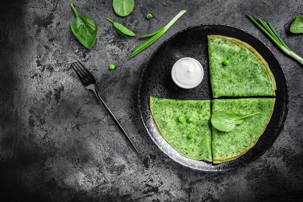 Crepes de panquecas verdes de espinafre com creme de leite. Delicioso café da manhã saudável. banner, lugar de receita de menu para texto, vista superior.