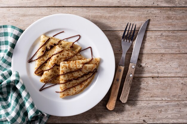 Crepes doces com chocolate em mesa de madeira