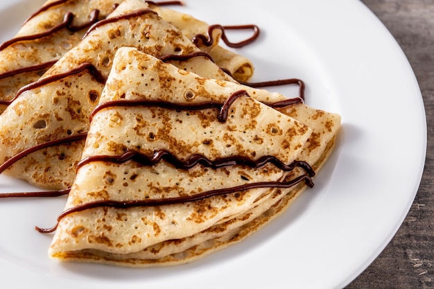 Foto crepes doces com chocolate na mesa de madeira