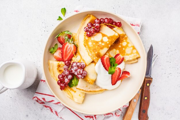 Crepes finos caseros servidos con crema de cuajada.