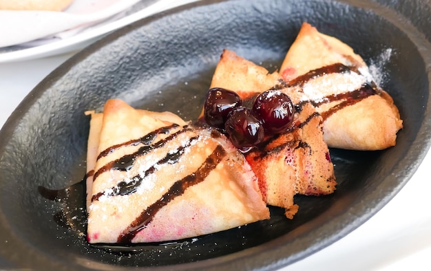 Crepes franceses com calda de chocolate e cerejas em um restaurante em receita de panquecas de Paris