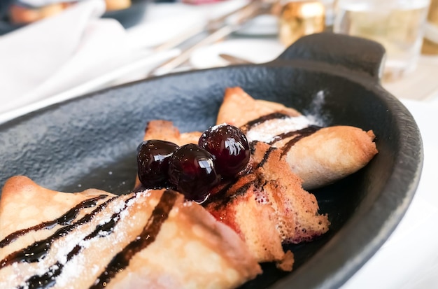 Crepes franceses con salsa de chocolate y cerezas en un restaurante en París receta de panqueques