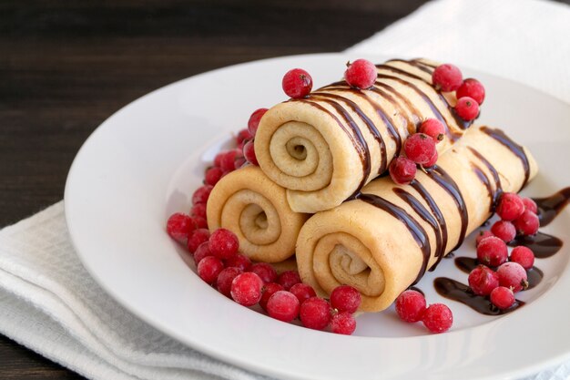 Crepes hechas en casa torcidas con el chocolate en una placa blanca.