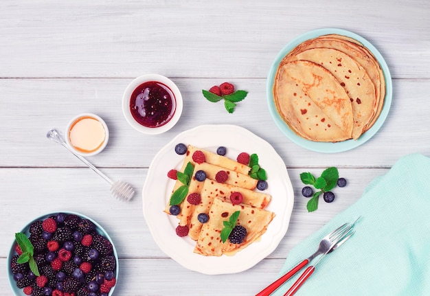 Crepes mit Beerenfrühstück selektiver Fokus auf einem weißen Holztisch horizontal keine Leute