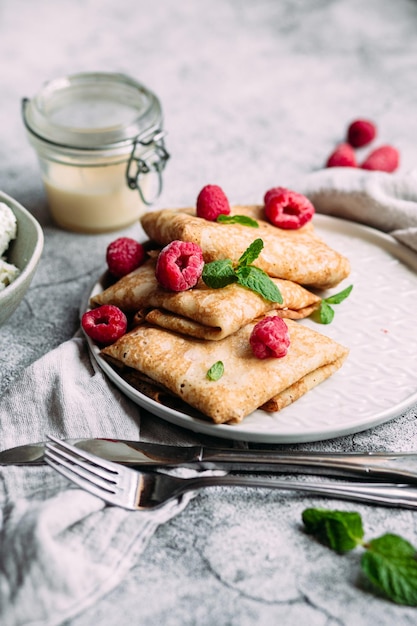 Crêpes mit hausgemachtem Hüttenkäse, Himbeeren ein grauer Teller