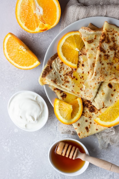 Crepes mit orangen, honig und naturjoghurt oder sauerrahm. dünne pfannkuchen.