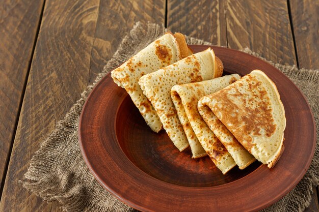 Crepes o Blini ruso sobre fondo de madera en estilo rústico. Crepes finas caseras para desayuno o postre.