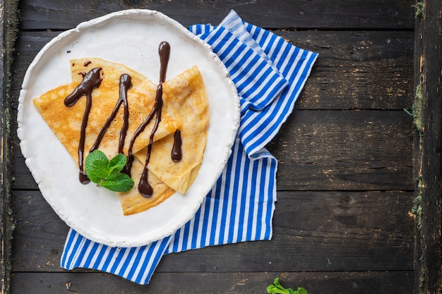 crepes panquecas finas despeje calda de chocolate prato branco bolo plano