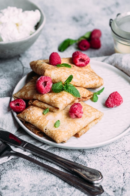 Crepes con requesón casero, frambuesas un plato gris