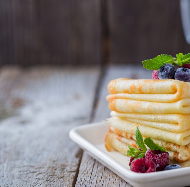 Crepes con salsa de fresa y crema. Crepes finos caseros para el desayuno o el postre en la pared de madera