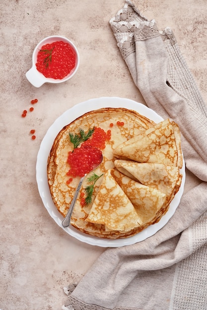 Crepes, tortitas finas, tortitas rusas con caviar rojo sobre placa gris. Fondo de mármol. Copie el espacio. Vista superior.