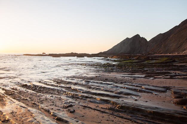 Crepúsculo nas rochas e mar na Praia da Amoreira, Algarve, Portugal