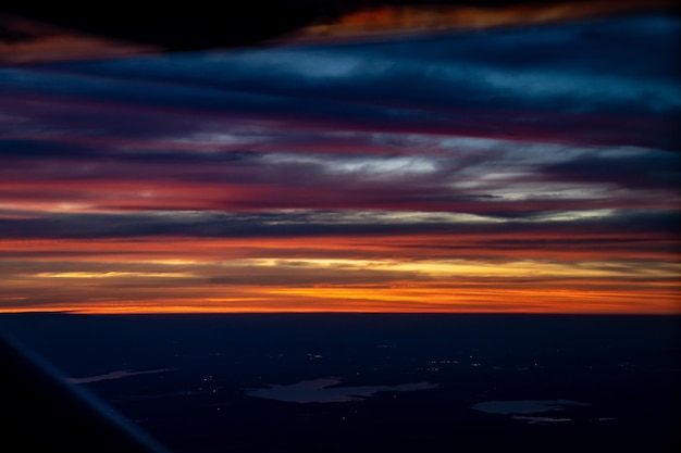 Crepúsculo a la noche desde el avión a reacción ver el cielo azul naranja rojo con la luz de la ciudad de Tailandia debajo