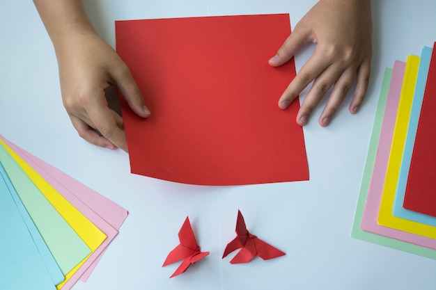 criação de origami uma borboleta. As mãos das crianças fazem origami uma borboleta.