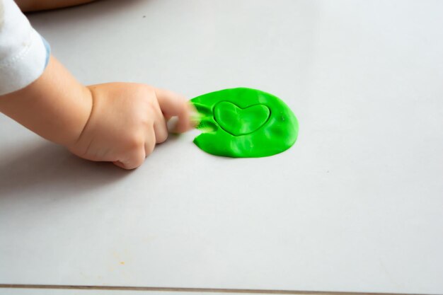 Foto criança a brincar com massa de brincadeira no chão em casa