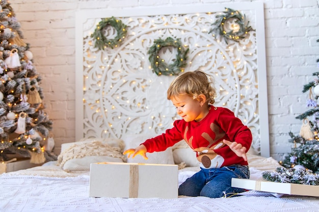 Criança abre presentes de Natal debaixo da árvore Foco seletivo