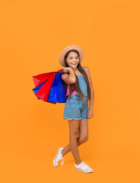 Criança adolescente alegre com sacos de compras em fundo amarelo de comprimento completo