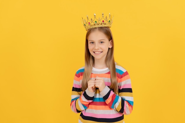 Criança adolescente alegre na coroa da rainha no fundo amarelo