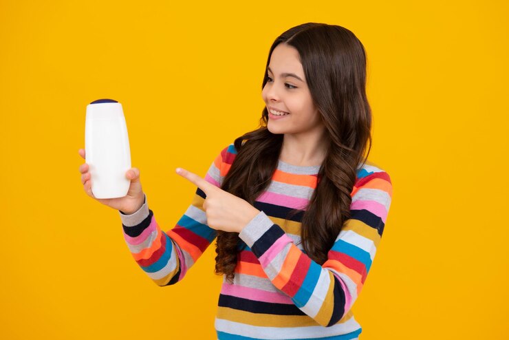 Foto criança adolescente com shampoos, condicionadores e gel de banho cuidados com o cabelo longo da adolescente apresentando frasco de shampoo de produto cosmético adolescente feliz emoções positivas e sorridente da adolescente