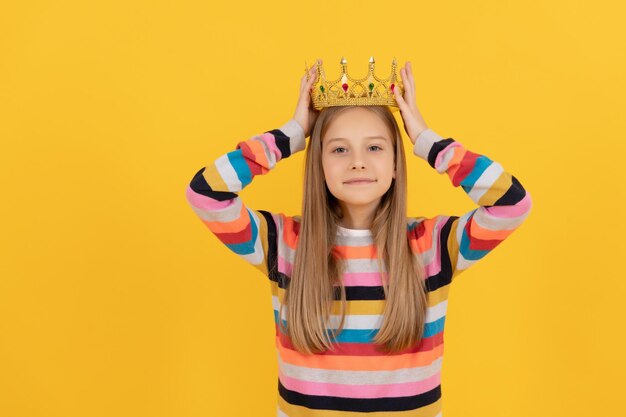 Criança adolescente egoísta na coroa da rainha em fundo amarelo