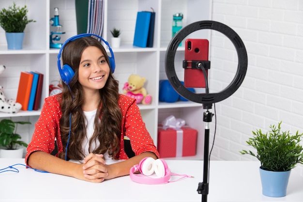 Criança adolescente gravando tutorial em vídeo para mídias sociais com smartphone Influenciador adolescente criando novo conteúdo para blog enquanto transmite online Garota feliz rosto positivo e sorridente